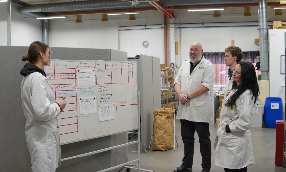 människor pratar framför en whiteboardtavla